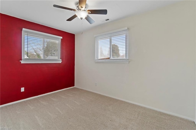 carpeted empty room featuring visible vents, baseboards, and ceiling fan