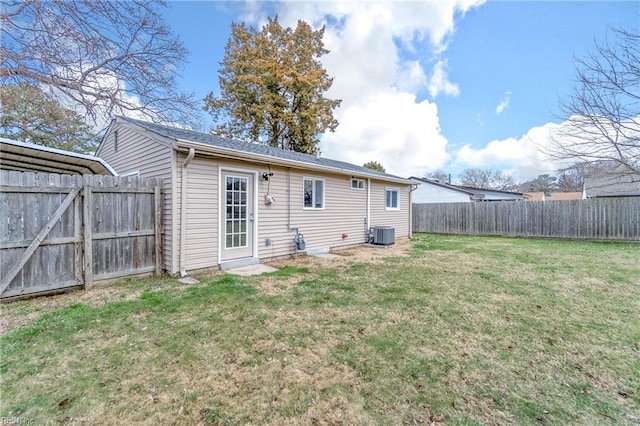 rear view of property featuring a yard, central AC unit, and a fenced backyard