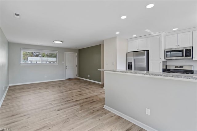 kitchen with stainless steel appliances, visible vents, light wood-style flooring, white cabinetry, and baseboards