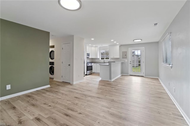 unfurnished living room with recessed lighting, visible vents, baseboards, light wood finished floors, and stacked washer and clothes dryer