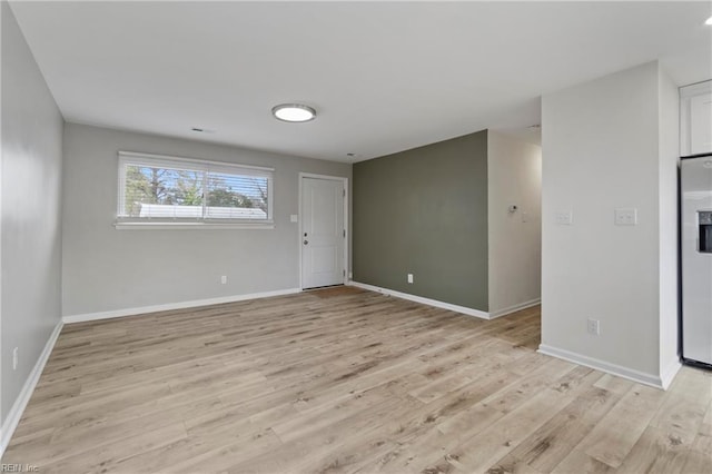 unfurnished room with light wood-style flooring and baseboards