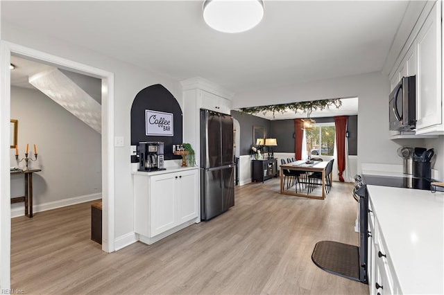 kitchen with light countertops, appliances with stainless steel finishes, light wood-style floors, and white cabinets