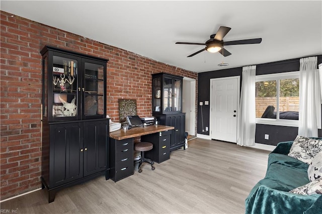 home office with brick wall, baseboards, ceiling fan, and light wood finished floors