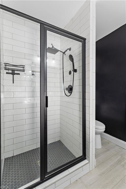 full bathroom featuring a stall shower, wood finished floors, toilet, and baseboards