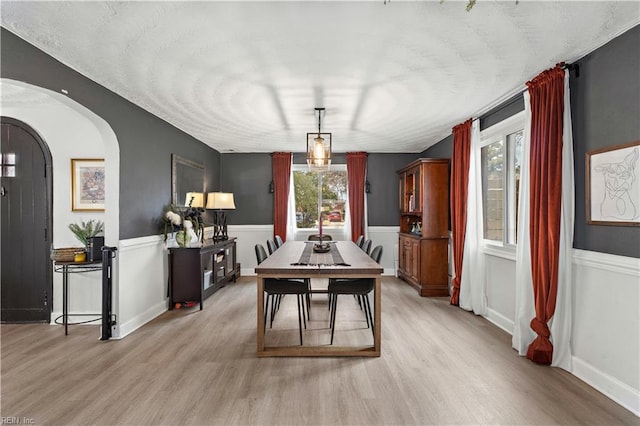 dining area with arched walkways, light wood finished floors, and a healthy amount of sunlight