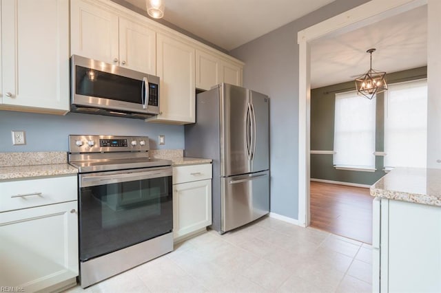 kitchen with light stone counters, baseboards, hanging light fixtures, appliances with stainless steel finishes, and an inviting chandelier