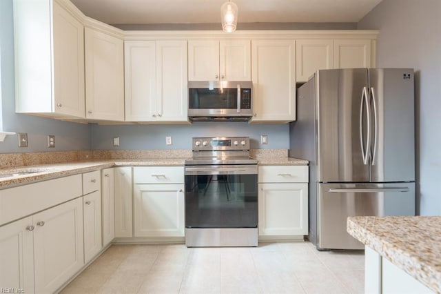 kitchen featuring light stone countertops, appliances with stainless steel finishes, a sink, and light tile patterned flooring