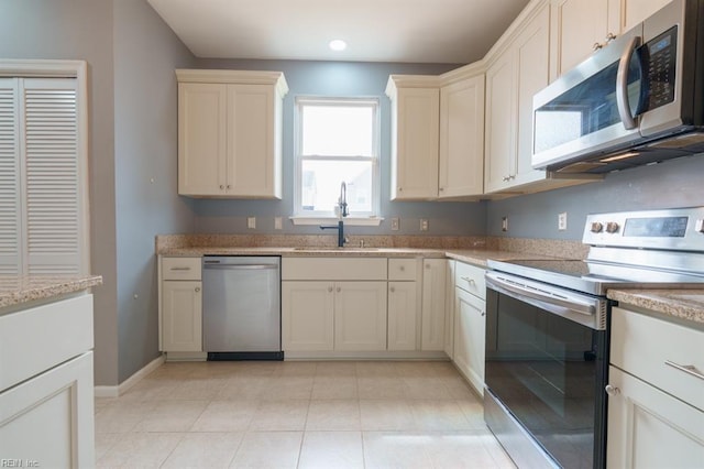 kitchen with light tile patterned floors, recessed lighting, stainless steel appliances, a sink, and baseboards