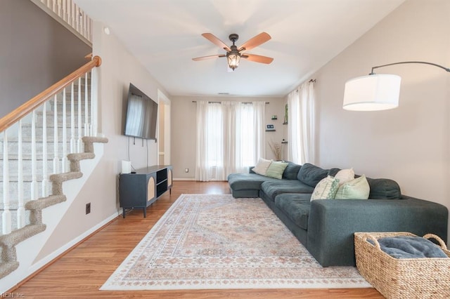 living area featuring ceiling fan, stairs, baseboards, and wood finished floors