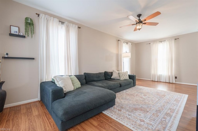 living area with ceiling fan, wood finished floors, and baseboards