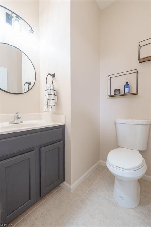 half bathroom with tile patterned flooring, vanity, toilet, and baseboards