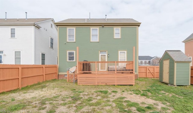 back of house with a deck, a fenced backyard, an outdoor structure, a yard, and a shed