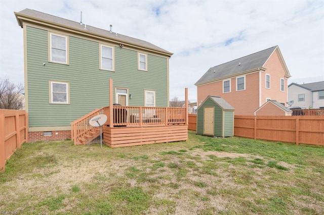 back of house featuring an outbuilding, a fenced backyard, a yard, a wooden deck, and a storage unit