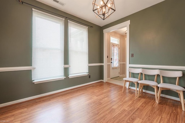 interior space with visible vents, baseboards, a chandelier, and wood finished floors