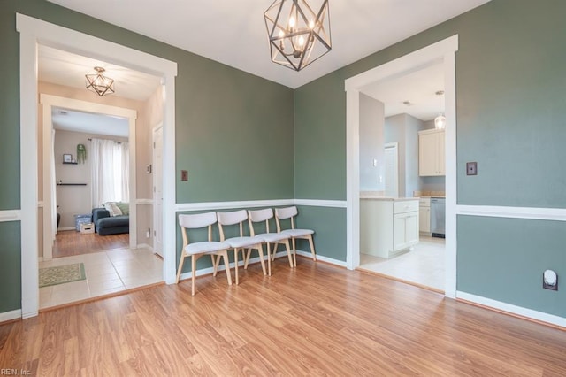 spare room featuring light wood finished floors, baseboards, and a notable chandelier