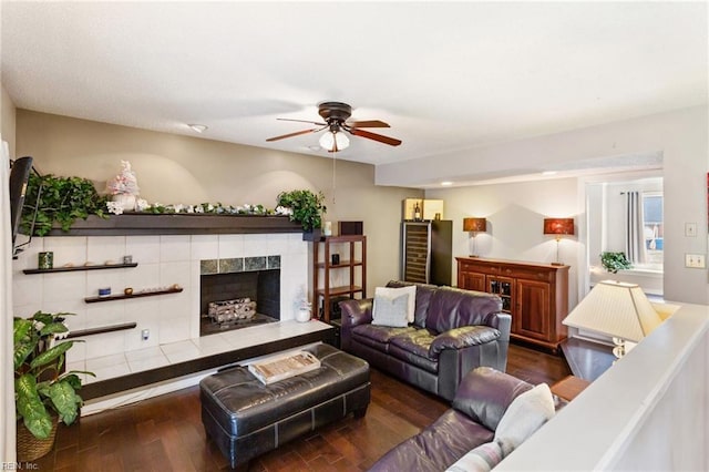 living room featuring a tiled fireplace, wood finished floors, and a ceiling fan