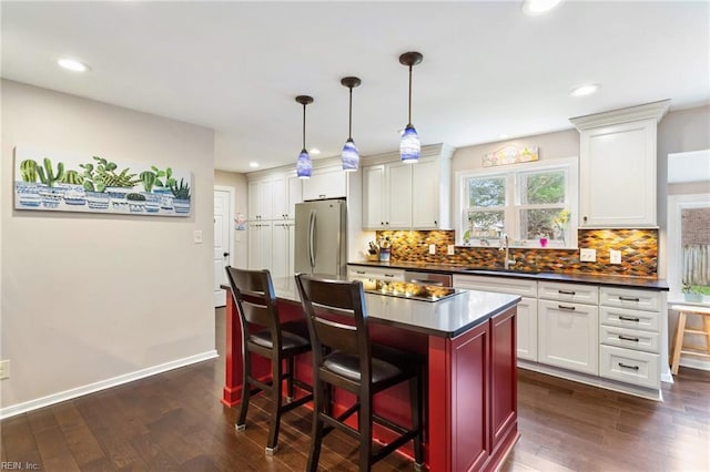 kitchen with dark countertops, dark wood-style floors, a sink, and freestanding refrigerator