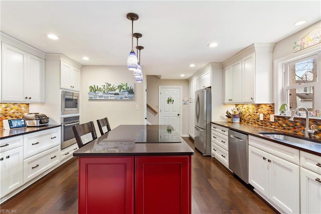 kitchen featuring dark wood-style flooring, stainless steel appliances, dark countertops, white cabinetry, and a sink