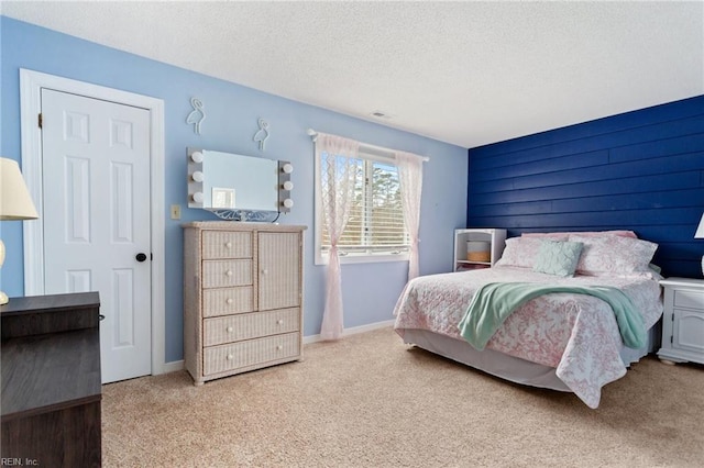 bedroom with carpet floors, visible vents, a textured ceiling, and baseboards