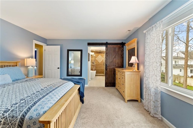 bedroom featuring light carpet, a barn door, and baseboards