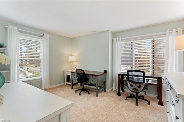 office space with light carpet, visible vents, a wealth of natural light, and baseboards