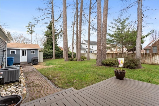 view of yard featuring a wooden deck, fence, central AC unit, and an outdoor structure