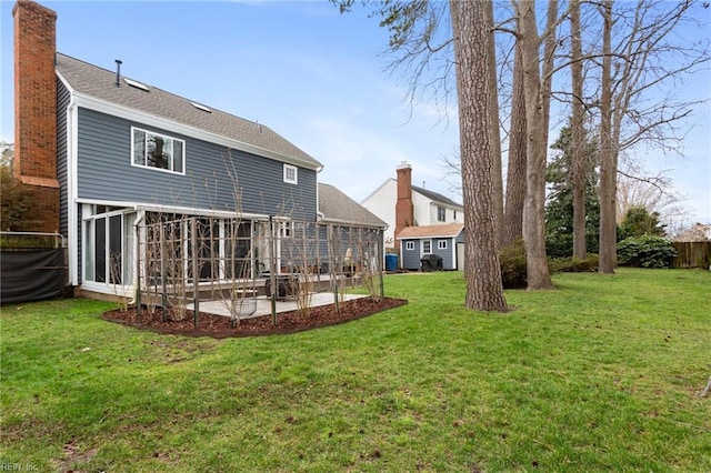 rear view of house with a sunroom, a chimney, fence, and a lawn