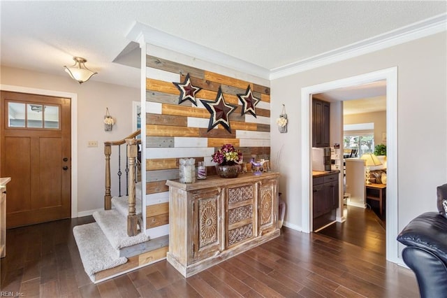 foyer entrance featuring dark wood-style flooring, wood walls, stairway, and a textured ceiling