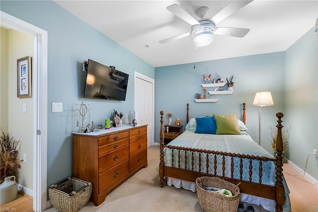 bedroom with a closet, light colored carpet, ceiling fan, and baseboards