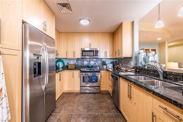 kitchen featuring visible vents, appliances with stainless steel finishes, light brown cabinets, a sink, and dark stone countertops