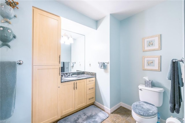 bathroom with tile patterned flooring, vanity, toilet, and baseboards