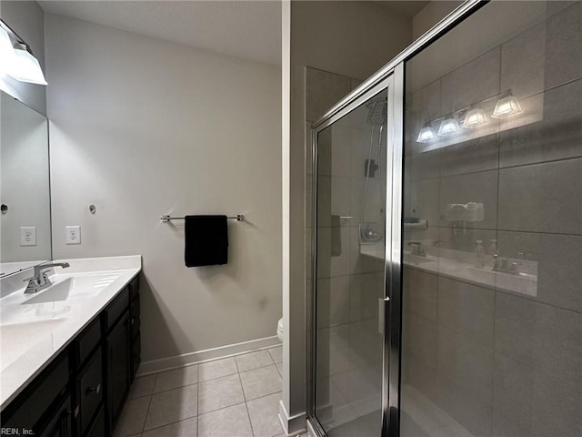 bathroom featuring double vanity, a stall shower, a sink, tile patterned flooring, and baseboards