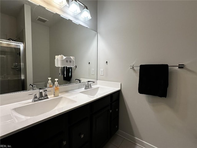 bathroom featuring tile patterned flooring, a sink, a shower stall, and double vanity