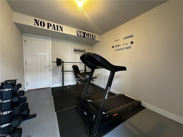 exercise room with a textured ceiling, visible vents, and baseboards