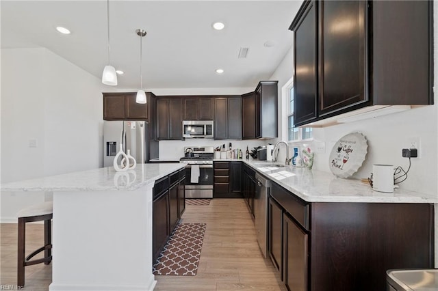 kitchen with dark brown cabinetry, light wood finished floors, appliances with stainless steel finishes, a center island, and a sink