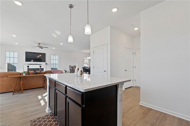 kitchen with a ceiling fan, a wealth of natural light, decorative light fixtures, and light wood finished floors