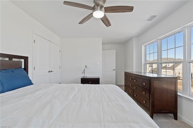 carpeted bedroom featuring a ceiling fan, a closet, visible vents, and baseboards