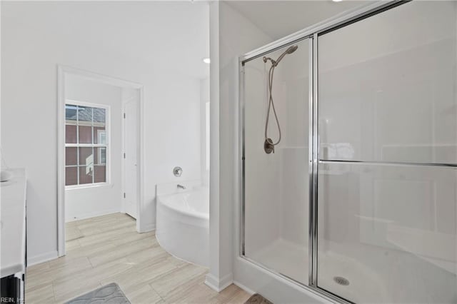 full bathroom featuring a stall shower, wood finished floors, and a bath