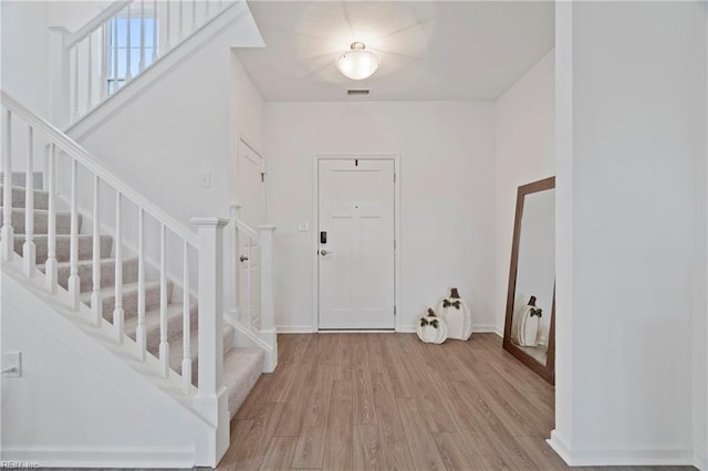 entrance foyer with baseboards, visible vents, stairway, and light wood finished floors