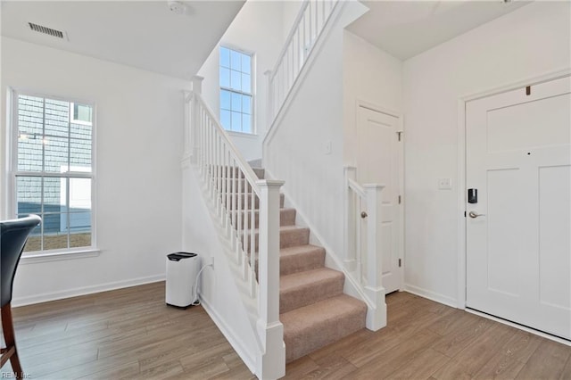 entryway with light wood finished floors, visible vents, stairway, and baseboards