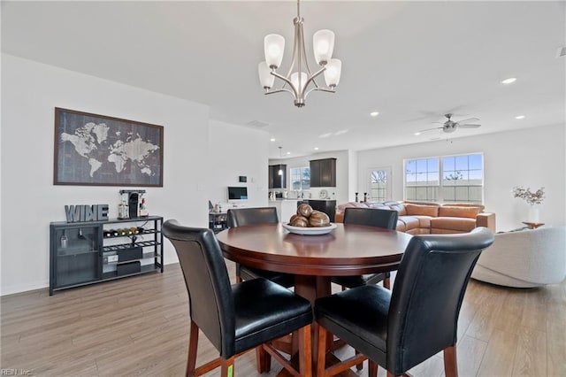 dining space featuring ceiling fan with notable chandelier, baseboards, light wood-style flooring, and recessed lighting