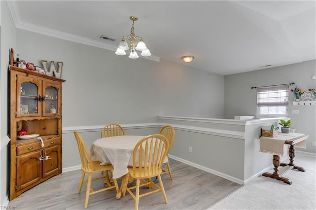 dining space featuring a chandelier, crown molding, light wood finished floors, and baseboards