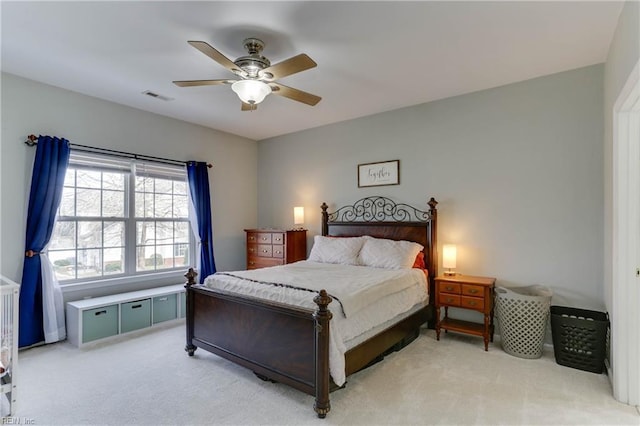 bedroom featuring a ceiling fan, visible vents, and light colored carpet