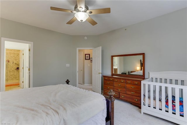 bedroom with ceiling fan, ensuite bath, and light colored carpet