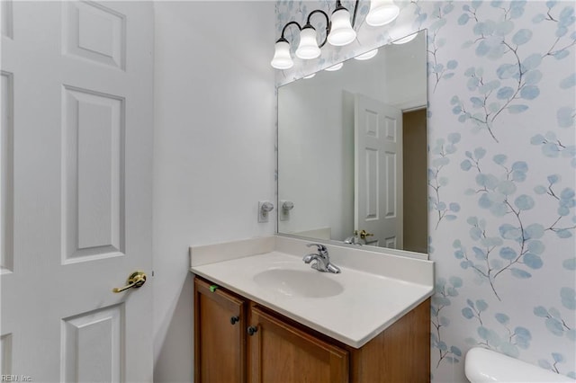 bathroom featuring toilet, vanity, and wallpapered walls