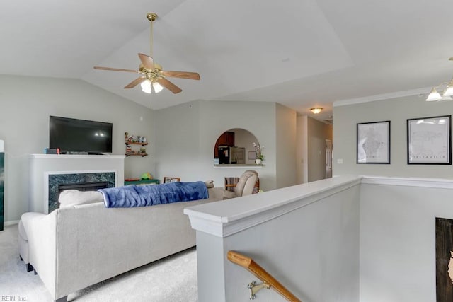 living area featuring light carpet, a fireplace, vaulted ceiling, and a ceiling fan