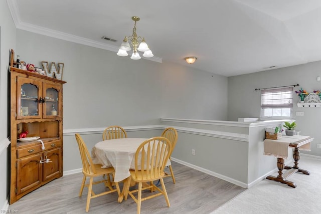 dining area with ornamental molding, light wood finished floors, an inviting chandelier, and baseboards