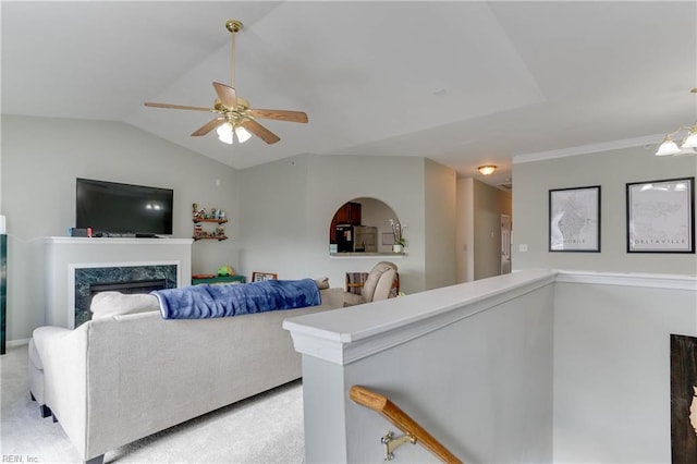 living room with vaulted ceiling, a fireplace, a ceiling fan, and light colored carpet