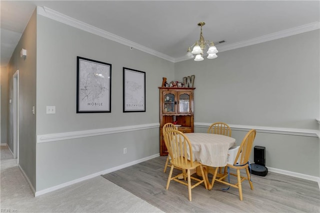 dining room with a chandelier, ornamental molding, wood finished floors, and baseboards