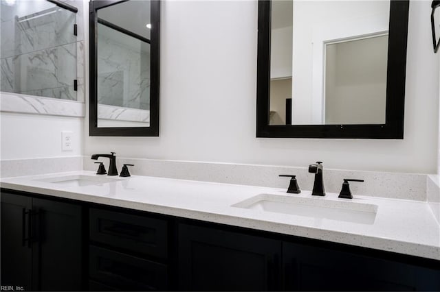 bathroom with double vanity, a sink, and a marble finish shower